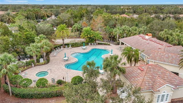 pool with a hot tub, fence, a wooded view, and a patio