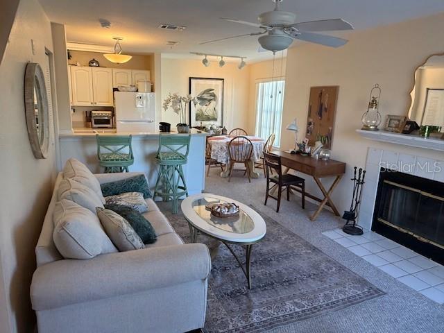 tiled living room with ceiling fan and a fireplace