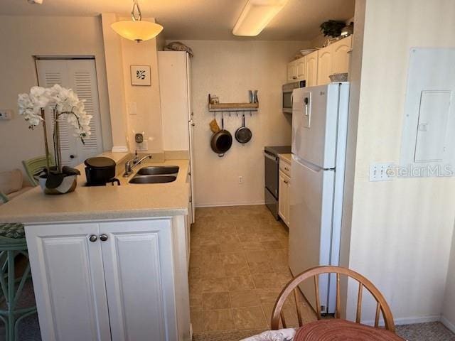 kitchen with electric range, sink, white refrigerator, decorative light fixtures, and white cabinets