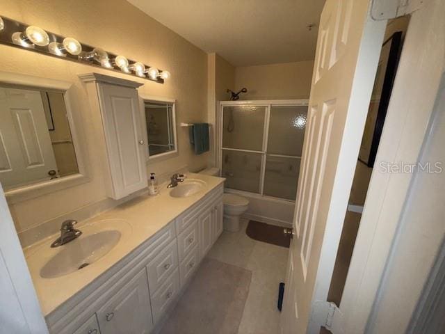 full bathroom with tile patterned flooring, vanity, toilet, and bath / shower combo with glass door