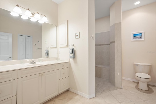 bathroom featuring tile patterned floors, vanity, a tile shower, and toilet