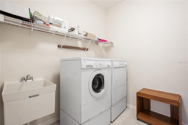 clothes washing area featuring washer and clothes dryer, light tile patterned floors, and sink