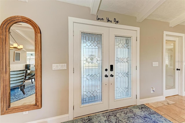 entryway featuring beam ceiling, french doors, and a textured ceiling