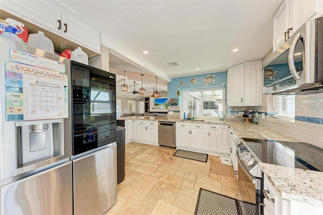 kitchen featuring appliances with stainless steel finishes, sink, white cabinets, light stone countertops, and tasteful backsplash