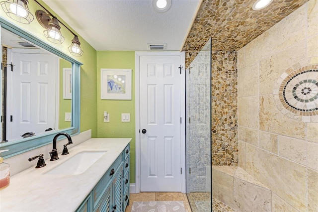 bathroom featuring vanity, a textured ceiling, and tiled shower