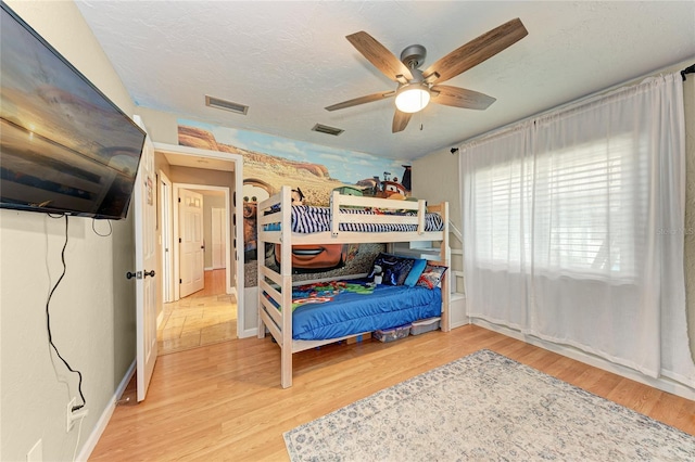 bedroom featuring hardwood / wood-style floors, ceiling fan, and a textured ceiling