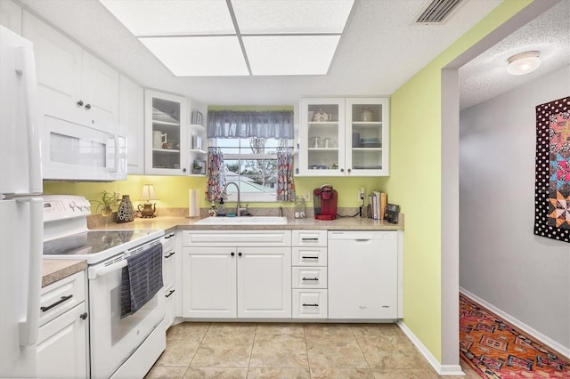 kitchen with white cabinetry, sink, a textured ceiling, white appliances, and light tile patterned floors