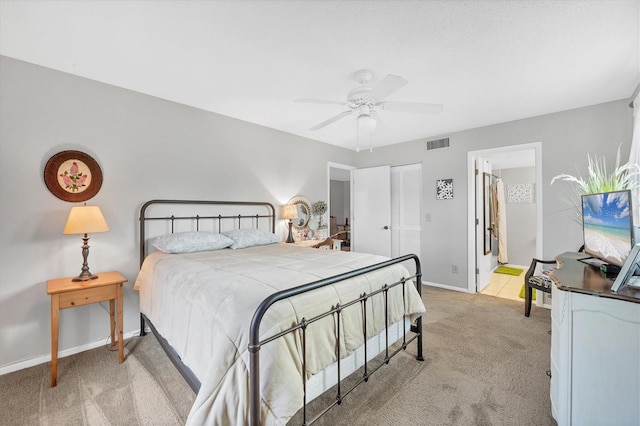 carpeted bedroom featuring ensuite bath and ceiling fan