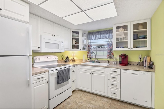 kitchen with white cabinetry, sink, light tile patterned floors, and white appliances