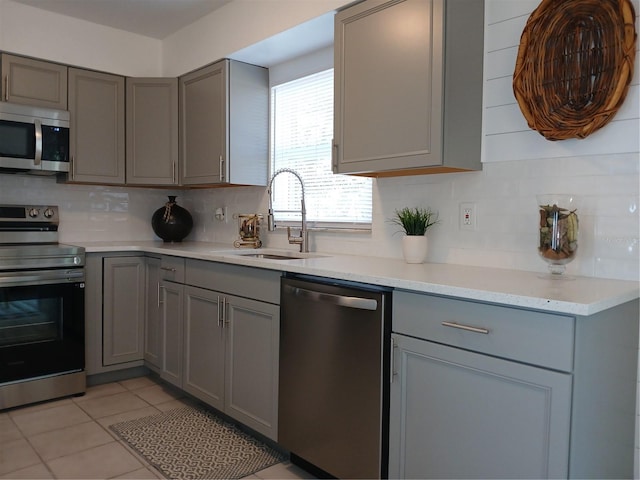 kitchen featuring sink, backsplash, gray cabinetry, and stainless steel appliances