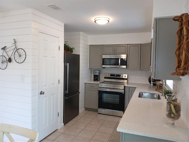 kitchen with light stone counters, light tile patterned floors, gray cabinets, and stainless steel appliances