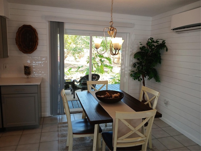 dining room featuring a wall unit AC, an inviting chandelier, light tile patterned floors, and wooden walls