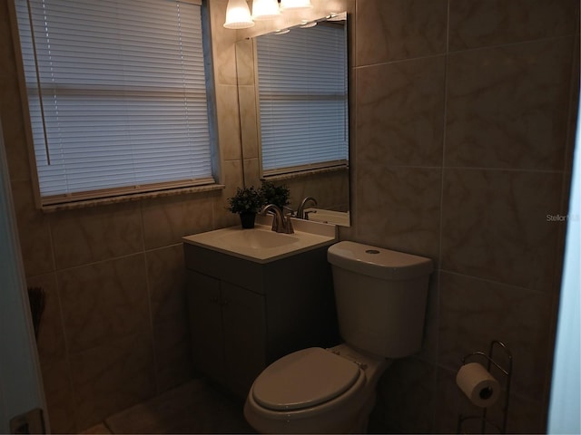 bathroom featuring toilet, tile walls, and vanity