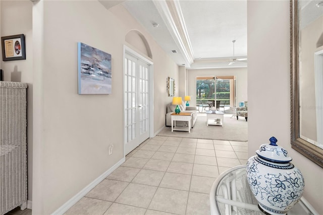 entryway featuring french doors, a raised ceiling, light tile patterned flooring, ceiling fan, and crown molding