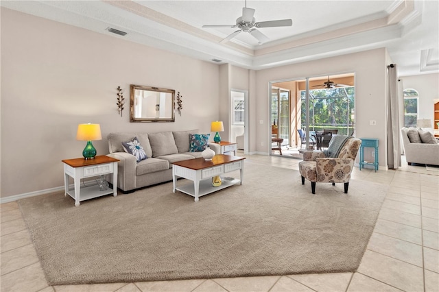 tiled living room with ceiling fan, crown molding, and a raised ceiling