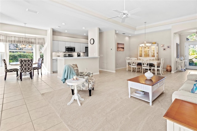 tiled living room with ceiling fan with notable chandelier, a tray ceiling, and crown molding