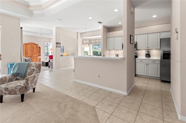 kitchen featuring white cabinets, crown molding, light tile patterned floors, and stainless steel fridge