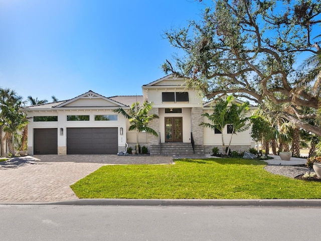 view of front of property with french doors, a garage, and a front lawn