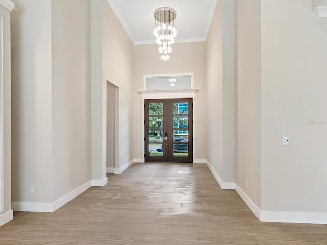 entrance foyer featuring a notable chandelier, ornamental molding, light hardwood / wood-style flooring, and french doors