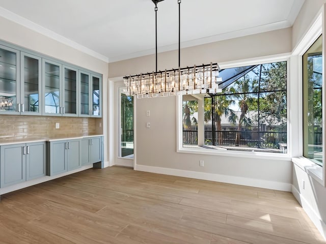 unfurnished dining area featuring crown molding, light hardwood / wood-style floors, and a notable chandelier