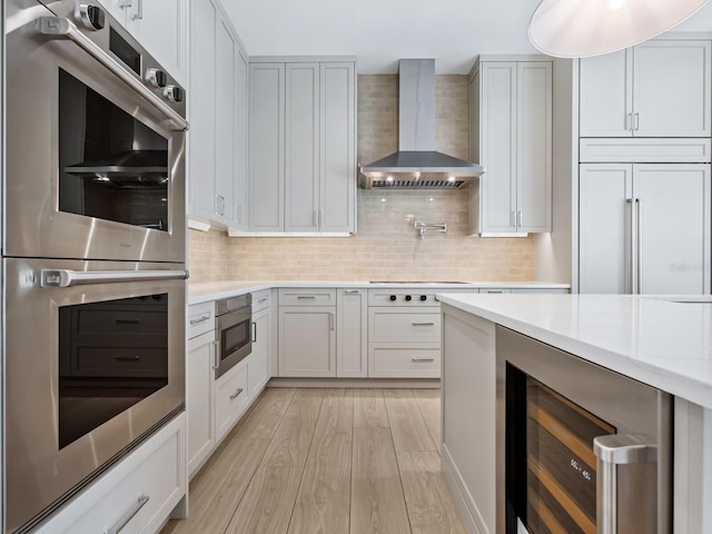 kitchen with wine cooler, wall chimney exhaust hood, paneled refrigerator, tasteful backsplash, and stainless steel double oven