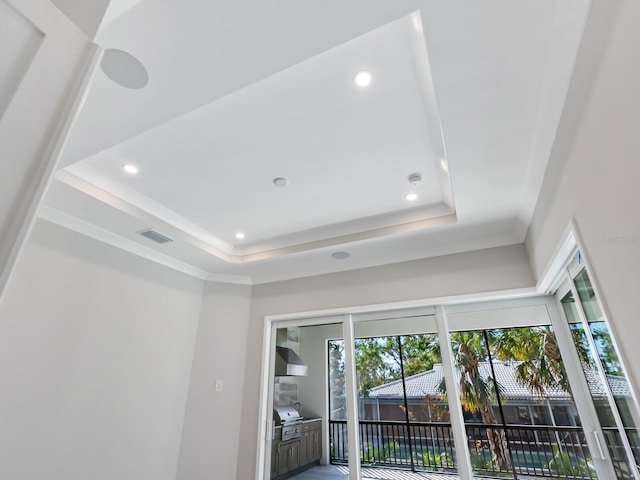 details featuring a raised ceiling and wall chimney exhaust hood