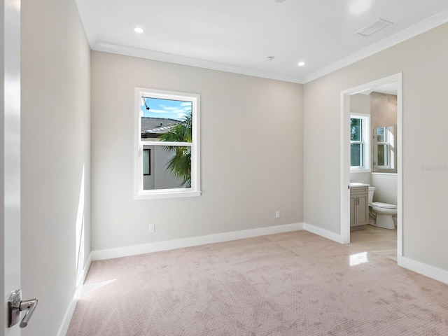 unfurnished bedroom featuring light carpet, ensuite bathroom, multiple windows, and ornamental molding