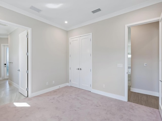 unfurnished bedroom with light colored carpet, ornamental molding, and a closet