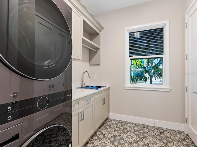 laundry area with sink, cabinets, light tile patterned floors, and stacked washer / dryer