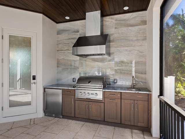 kitchen with wooden ceiling, refrigerator, sink, wall chimney exhaust hood, and tile walls