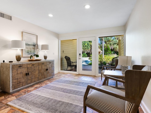 sitting room with stone tile floors, visible vents, baseboards, and recessed lighting