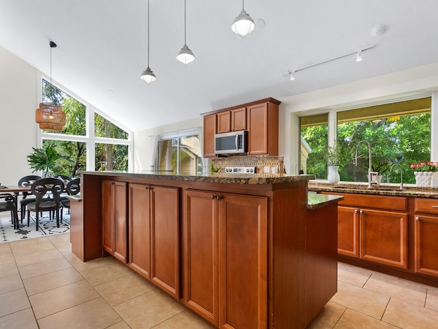 1214 Sea Plume Way, Sarasota, FL 34242 - kitchen with stainless steel microwave, dark stone counters, light tile patterned floors, tasteful backsplash, and a center island