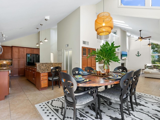 dining space featuring ceiling fan, light tile patterned floors, and high vaulted ceiling