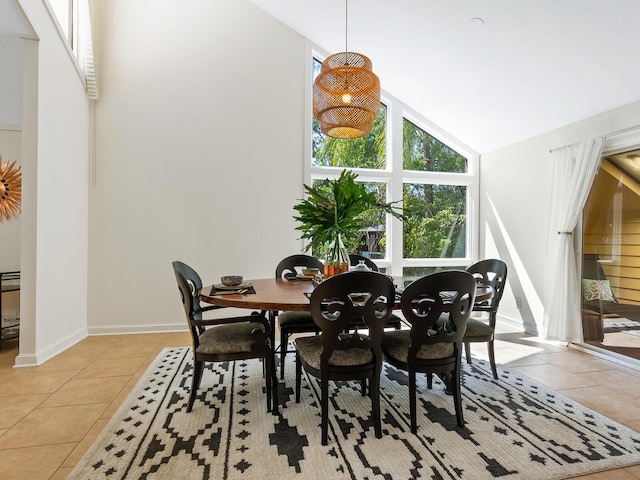 dining area featuring light tile patterned floors, baseboards, and high vaulted ceiling