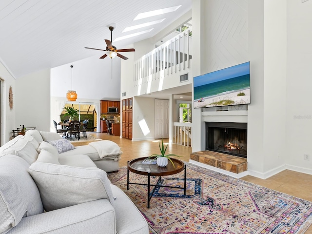 1214 Sea Plume Way, Sarasota, FL 34242 - living room featuring high vaulted ceiling, a ceiling fan, a tiled fireplace, light tile patterned floors, and a skylight