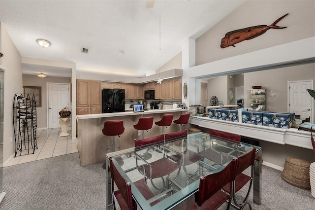 carpeted dining room with high vaulted ceiling