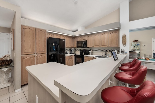 kitchen featuring vaulted ceiling, sink, a breakfast bar, black appliances, and kitchen peninsula