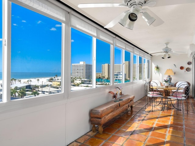 sunroom / solarium featuring ceiling fan and a water view