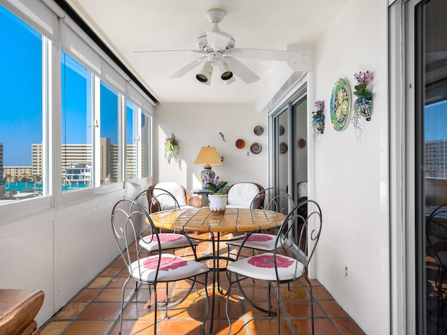 dining space with ceiling fan and dark tile patterned flooring