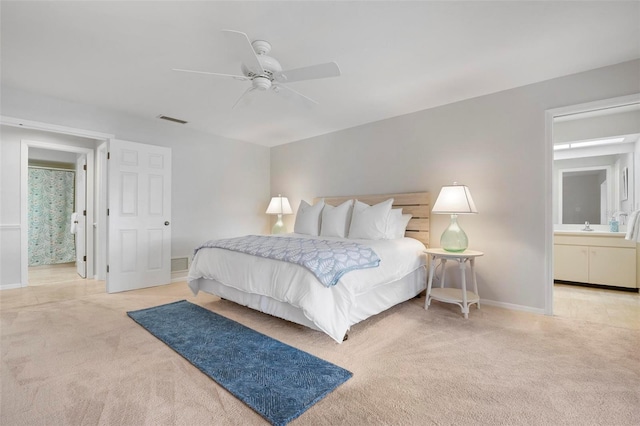 bedroom with ensuite bathroom, ceiling fan, and light colored carpet