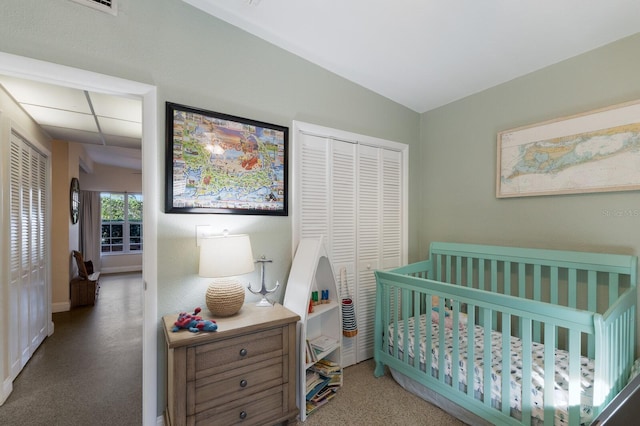 carpeted bedroom featuring a crib, vaulted ceiling, and a closet