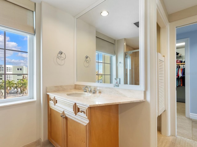 bathroom featuring vanity, tile patterned floors, a wealth of natural light, and a shower with shower door