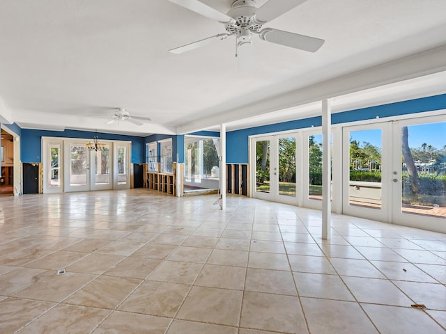 unfurnished living room featuring french doors, light tile patterned floors, and ceiling fan with notable chandelier