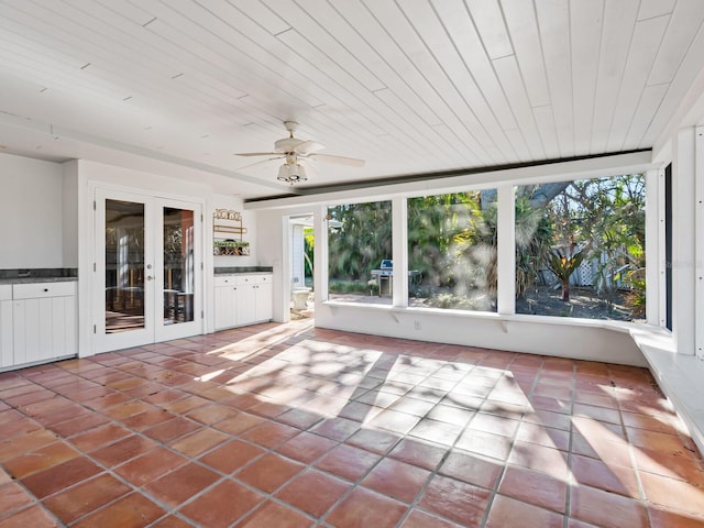 unfurnished sunroom with ceiling fan, wood ceiling, and french doors