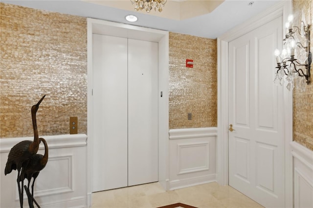 doorway to outside with elevator, light tile patterned floors, and a chandelier