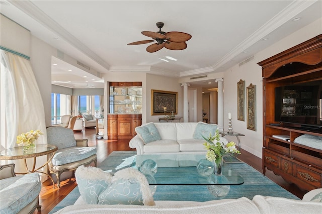 living room with a raised ceiling, crown molding, hardwood / wood-style floors, and ceiling fan