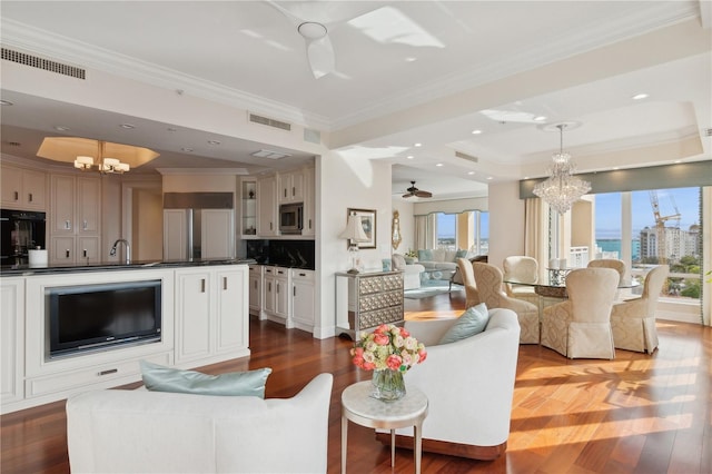 living room featuring hardwood / wood-style floors, plenty of natural light, ornamental molding, and ceiling fan with notable chandelier