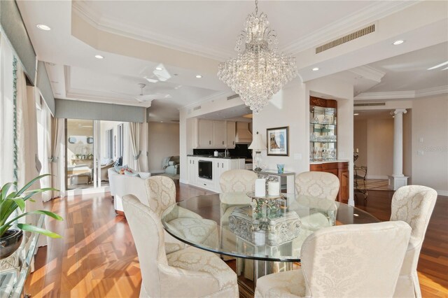 dining room featuring an inviting chandelier, light hardwood / wood-style flooring, ornate columns, and ornamental molding