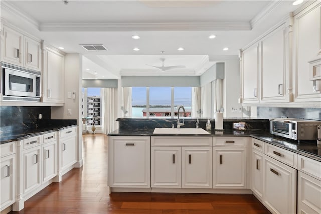 kitchen featuring white cabinetry, stainless steel microwave, dark wood-type flooring, and sink