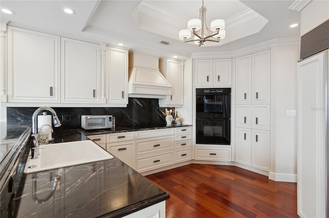 kitchen featuring sink, a raised ceiling, dark hardwood / wood-style flooring, black appliances, and custom exhaust hood